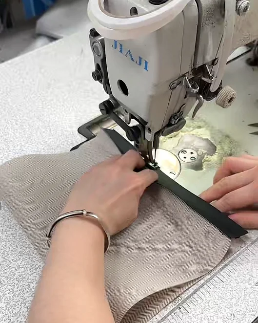 Hands guiding bag material through an industrial sewing machine