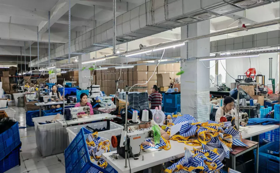 Workers sewing bag components on the production floor